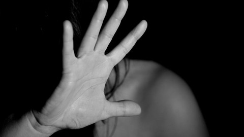 Das Bild zeigt eine Person, die zu ihrem eigenen Schutz eine Hand vors Gesicht hält.