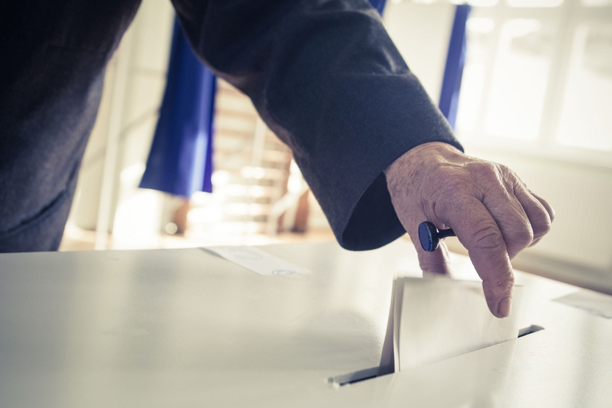 Eine Person wirft einen Wahlzettel in eine Wahlurne.