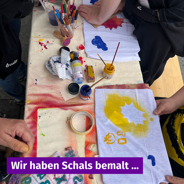 Bunt bemalte Schals auf einem Tisch voller Farben und Schablonen