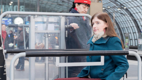 Eine Frau im Rollstuhl wird von einer Mitarbeiterin der Bahn in den Zug begleitet.